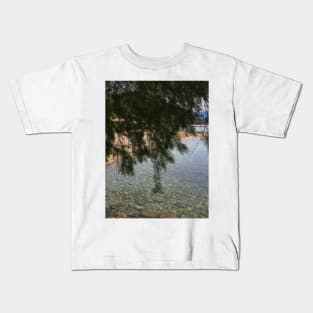 Stone sea surface in pristine clear water under a fir tree Kids T-Shirt
